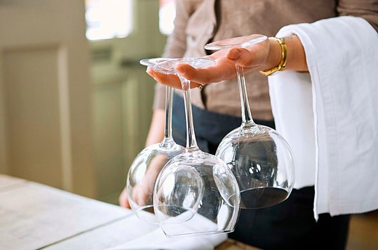 A Person Holding 3 Wine Glasses Upside Down While Cleaning to Entertain Guests